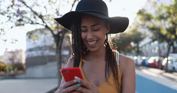 Bohemian mixed race girl using smartphone outdoor with city in background