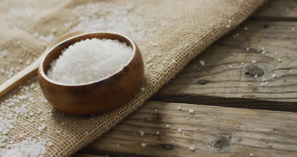 Video of salt in a bowl and spoon on wooden background