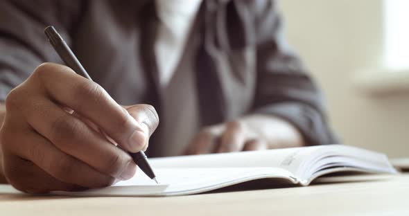 Close-up Male Hand Holds Pen Makes Notes on Sheet of Paper Signs Document. Cropped Frame African