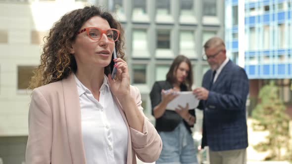 Portrait of a Middleaged Businesswoman Talking on a Mobile Phone in the Courtyard of a Large