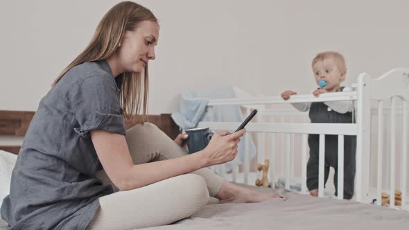 Mom Relaxing When Boy Sitting in Crib