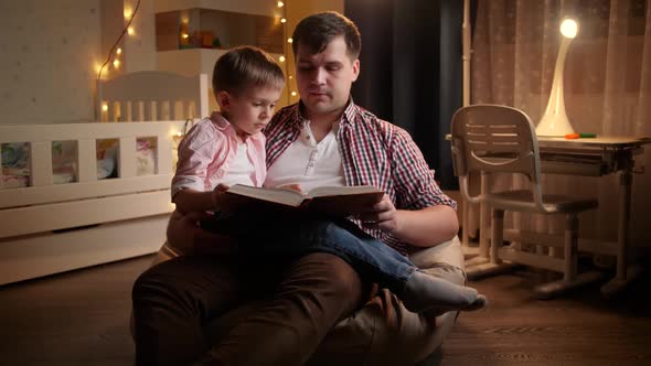 Smiling Little Boy Listening To Bedtime Story His Father Is Reading To Him at Night