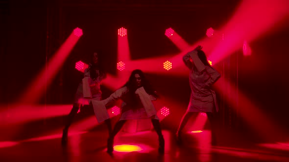 Silhouettes of a Three Charming Girls in White Shirt Are Dancing on the Stage. Shot in a Dark Studio