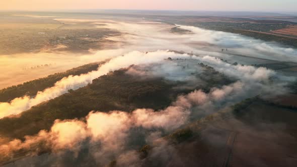 Aerial drone view of nature of Moldova at sunset. River and lush fog above it, village, greenery