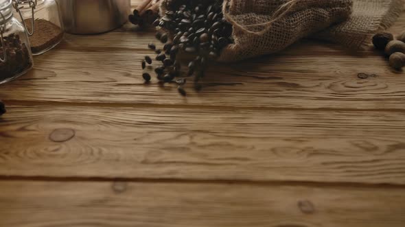 Roasted Coffee Beans Falling Down with Jute Sack on Wooden Table