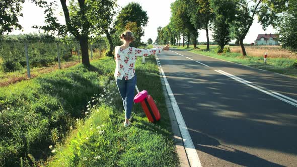 Traveler Girl Hitchhiking on a Sunny Road and Walking alt