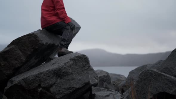 Hiker Sitting On Rock By Misty Fjord