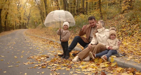 Happy Family Sitting on the Alley in the Autumn Park