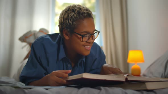 African American College Student Doing Homework on Bed at Home