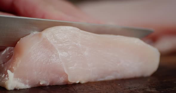 Men's Hands with Knife Cut Raw Chicken Fillet Into Pieces. 