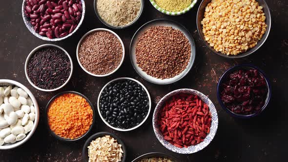 Various Superfoods in Smal Bowls on Dark Rusty Background