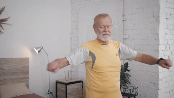 Old Handsome Man Leads a Healthy Lifestyle and Does Useful Exercises for Health and Vitality in Room