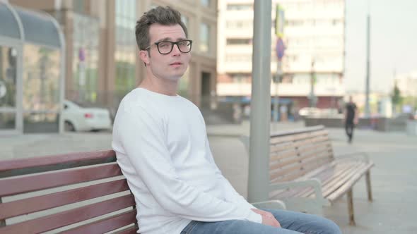 Rejecting Young Man Shaking Head in Denial While Sitting on Bench