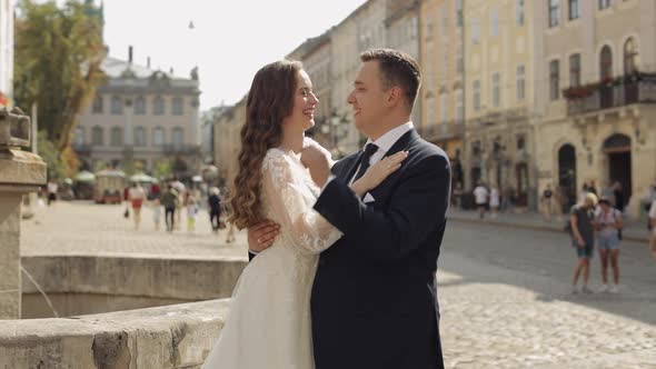 Newlyweds Caucasian Groom with Bride Standing Embracing Hugs on City Street Wedding Couple