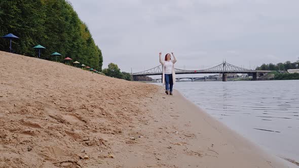 Young Woman is Walking Along City Beach