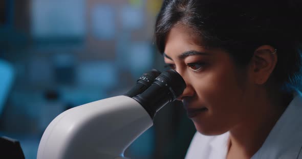 Female Research Scientist Looking at Samples Under Microscope