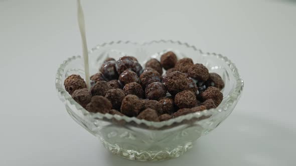 Milk Pouring on Chocolate Cocoa Balls in Glass Bowl