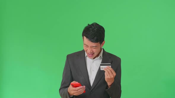 Asian Business Man Using Mobile Phone With Credit Card And Celebrating In The Green Screen Studio