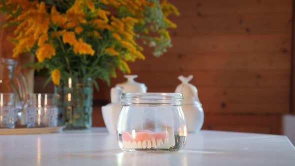 Hand putting dentures in glass of water