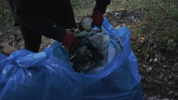 Cinematic Shot Closeup of Hand Picking Up Trash in the Forest Near the Lake