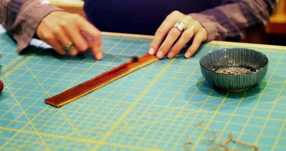 Mid-section of craftswoman preparing leather belt