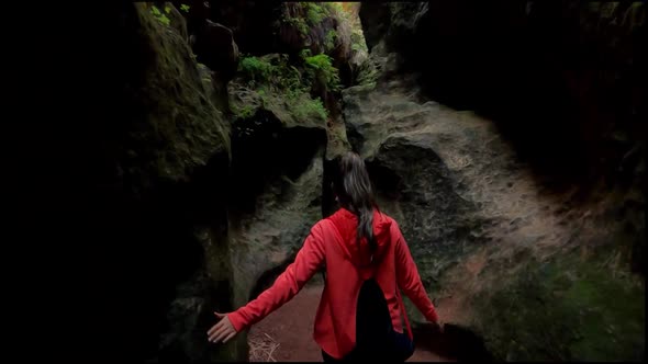 Young explorer walks through a narrow path in caves and caverns in Estrecho de la Arboleja, Spain.