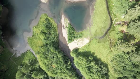 Summer drought reveals the exposed shoreline of a hidden mountain lake, aerial god view