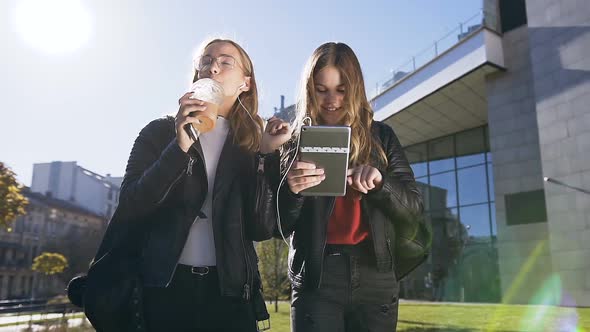 Happy Teenage Friends Walking and Using Tablet Computer Computer at Park in Centre of the Town