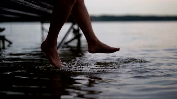 Relax in Nature Man is Sitting on Wooden Pier and Bathing Feet in Water of Sea or Lake