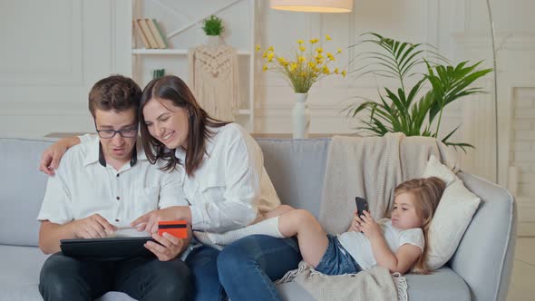 Parents Shopping Online While Their Daughter Plays in a Phone Online Game