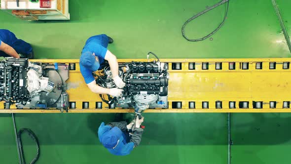 Top View of Workers Using a Conveyor To Assemble a Car Engine