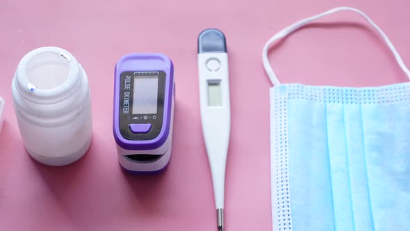 Surgical Masks Thermometer and Hand Sanitizer on Color Background