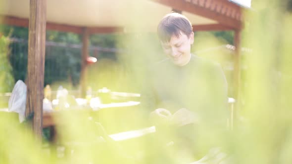 Travelling Young Guy Is Standing Near the Barbecue in Which Coals Are Smoking