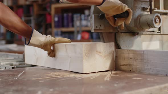 Hand of a Carpenter Cuts a Wooden Beam with the Circular Saw
