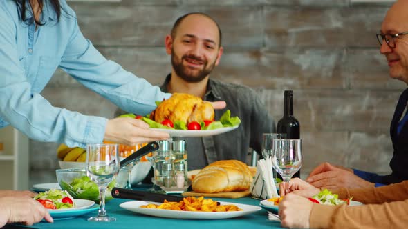 Young Wife Putting Tasty Chicken on the Table