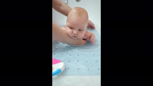 Father Washes Baby Daughter in Bathtub Holding Under Belly