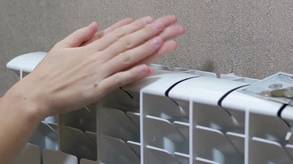 A Woman Warms Arms on Battery Heater at Home in Room