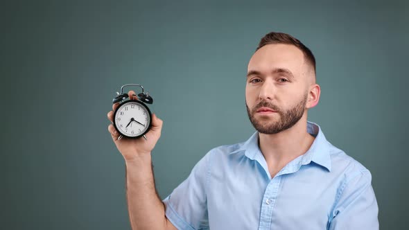 Focused Bearded Man Holding Alarm Clock Showing Time Deadline