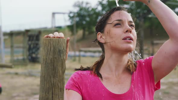 Caucasian woman pouring water on her face at bootcamp