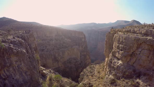 Aerial view of a woman balancing while tightrope walking and slacklining across a canyon