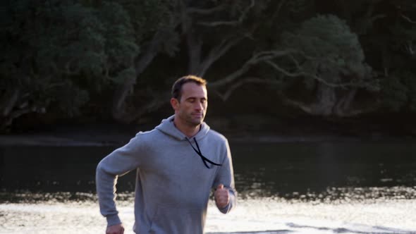 Slow motion shot of caucasian man running on the beach in Auckland, New Zealand