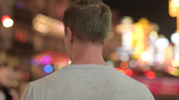 Closeup Rear View of Young Tourist Man Looking Around the Streets of Chinatown at Night