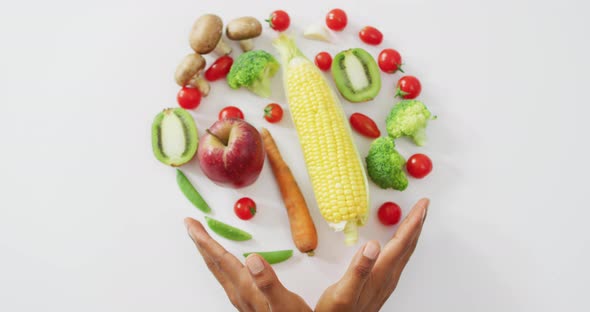 Video of biracial man's hands and fresh fruit and vegetables on white background