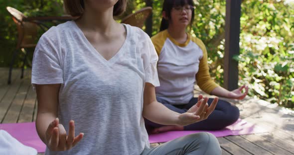 Asian mother and daughter meditating together in garden