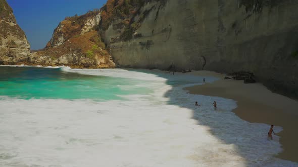 Tourist People Swim in Big Waves on Diamond Beach in Nusa Penida Island, Bali in Indonesia. Aerial