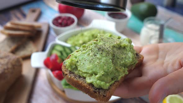 Peppering An Avocado Toast In A Hand.