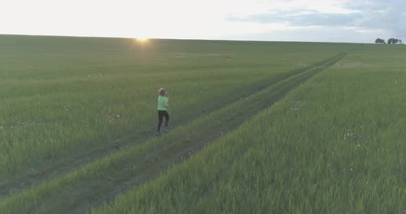 Sporty Child Runs Through a Green Wheat Field. Evening Sport Training Exercises at Rural Meadow. A