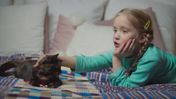 Adorable Girl Petting Cute Kitten with Love on Bed