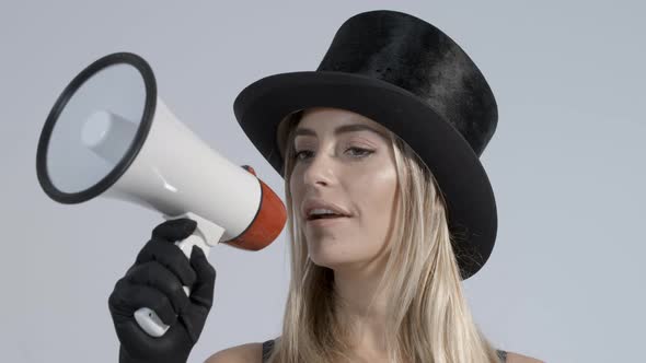 Young Woman Wearing Black Top Hat and Fishnets Using Megaphone