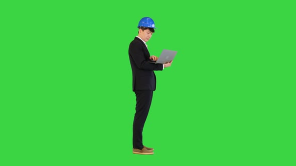 Engineer in a Suit Standing and Working on a Laptop on a Green Screen Chroma Key